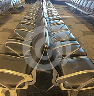 Two rowa of black leather chairs with metal hand rests lined up against each other