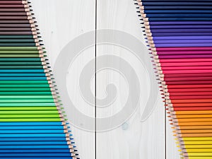 Two rows of colored pencils on wooden background