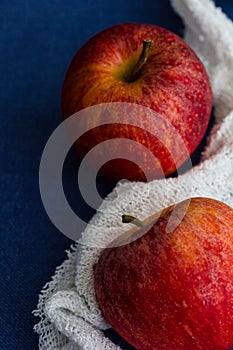 Two royal gala apples with a white cloth against a blue background. Close up, copy space