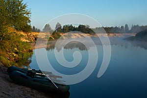 Two rubber boats with fishing tackle in the early morning during the fog, parked on the banks of the river