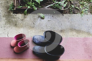 Two rubber boots pairs father and daughter on the porch at the entrance of the house during a rainy day4