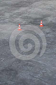 Two rubber traffic cones on grey asphalt