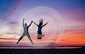 Two running and jumping girlfriends on the sunset sea beach. Hand in hand concept image