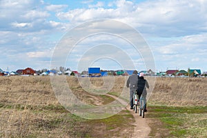 Two Russian pensioners ride their bicycles to their dacha across the field