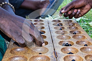 Two Rwandan Men`s Hands Shown Playing a Local Board Game Called Igisoro