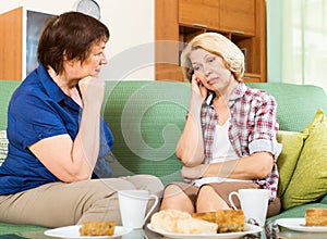 Two sad aged women chating on couch