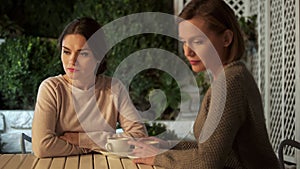 Two sad ladies sitting outdoors after quarrel, communication problem, conflict