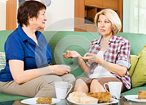 Two sad mature women chating on couch