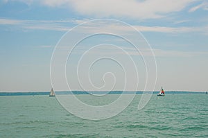Two sailing boats on foreground under beautiful blue sky with clouds. Yachting competition on Lake Balaton, Hungary.
