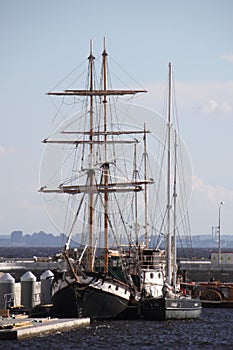Two sailing ships are moored to each other at the pier