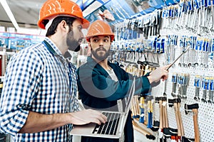 Two salesmen are checking equipment selection in power tools store.