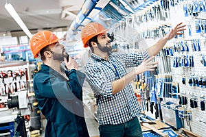 Two salesmen are checking equipment selection in power tools store.