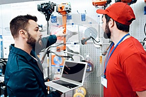 Two salesmen are checking tooks inventory with laptop in power tools store.