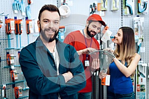 Two salesmen are showing female client new rake in power tools store.