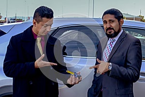 Two salesmen standing in front of a car.