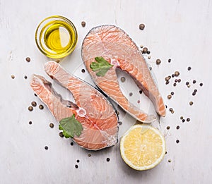 Two salmon steak, butter, pepper and salt, lemon, herbs on wooden rustic background top view close up