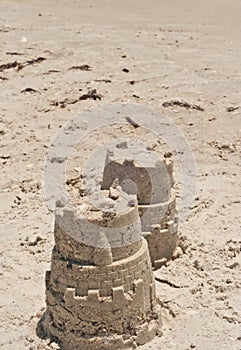 two sand castles, a young boy created with a plastic pail