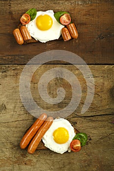 Two sandwiches Fried eggs with sausages and tomatoes with herbs on a piece of bread on a wooden table.