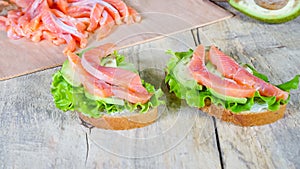 Two sandwiches with salmon, green salad and avocado closeup