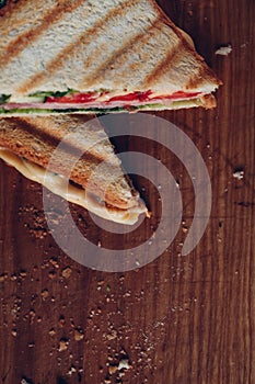Two sandwiches on a wooden background, top view. Stack of panini with ham, cheese and lettuce sandwich on a cutting board