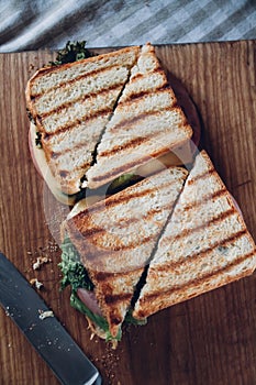 Two sandwiches on a wooden background, top view. Stack of panini with ham, cheese and lettuce sandwich on a cutting board