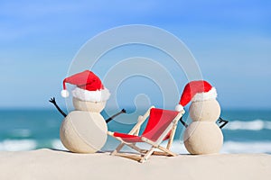 Two Sandy Christmas Snowmen are enjoying the beach