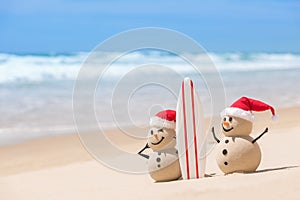 Two Sandy Christmas Snowmen are watching the waves