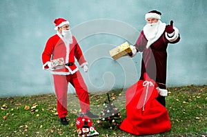 Two Santa Claus collect a big bag of gifts for Christmas.