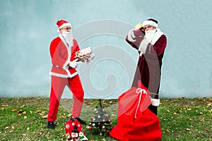 Two Santa Claus collect a big bag of gifts for Christmas.