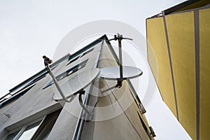 Two Satellite dishes and antennas on display at the top of a residential building. These are used for communications and satellite