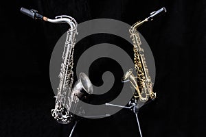 Two saxophones standing isolated in black