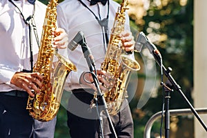 Two saxophonists playing at a jazz festival in a city park