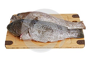 Two scaled grouper fish on bamboo cutting board