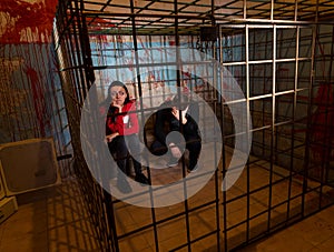 Two scared Halloween victims imprisoned in a metal cage