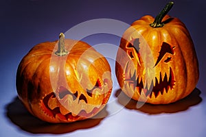 Two scary Halloween pumpkins with shadows on a coloured backgrou