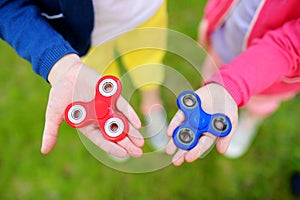 Two school children playing with fidget spinners on the playground. Popular stress-relieving toy for school kids and adults.