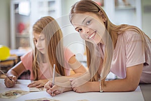 Two school girls writing during class