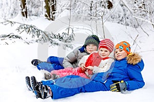 Two school kid boy and little toddler girl in winter forest. Happy children having fun with snow outdoors in winter