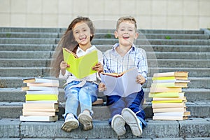 Two schoolchildren read books and laugh. The concept is back to school, education, reading, friendship and family photo