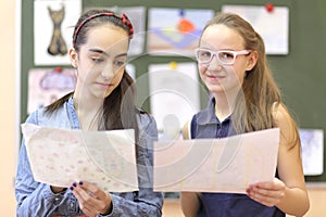 Two schoolgirls consider drawings on drawing photo