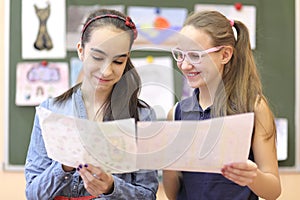 Two schoolgirls consider drawings on drawing photo