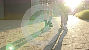 Two schoolgirls of different ages go to school holding hands. The older sister helps the younger one.