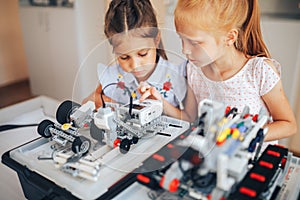 Two schoolgirls study in a robotics class, assemble a robot constructor