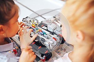 Two schoolgirls study in a robotics class, assemble a robot constructor