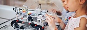 Two schoolgirls study in a robotics class, assemble a robot constructor