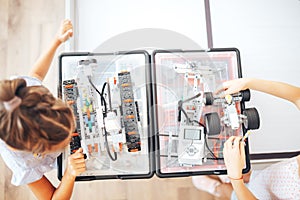 Two schoolgirls study in a robotics class, assemble a robot constructor