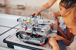 Two schoolgirls study in a robotics class, assemble a robot constructor