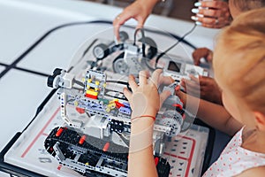 Two schoolgirls study in a robotics class, assemble a robot constructor