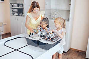 Two schoolgirls study in a robotics class, assemble a robot constructor