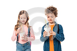 Two schoolkids with backpacks holding milkshakes isolated on white.